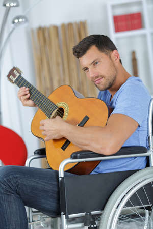 Man in wheelchair playing acoustic guitarの写真素材