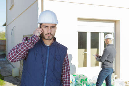 young handsome architect supervising a construction using cell phone outdoorsの写真素材
