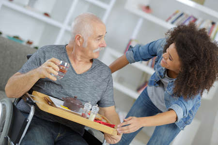 female caretaker serving breakfast to senior man at nursing homeの写真素材