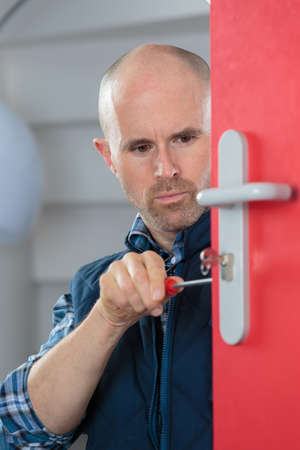 male carpenter fixing lock in doorの写真素材