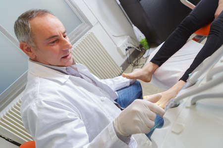 woman receives foot examination from gloved podiatristの写真素材