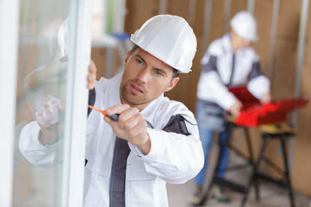 construction worker installing window in houseの写真素材