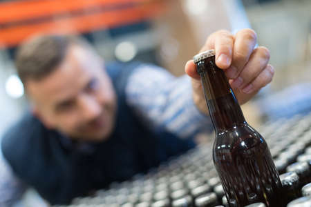 young drunk businessman is reaching a bottle of beerの写真素材