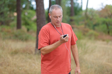 senior runner in nature with smart phone and earphonesの写真素材