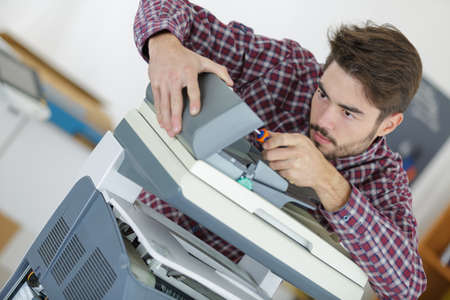 man mending the fax machineの写真素材