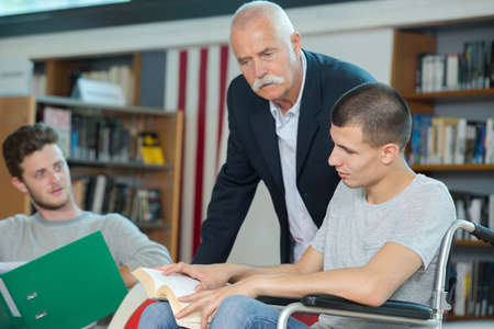 young man reading a book while the teacher is observingの写真素材