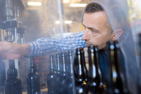 Worker righting bottle on production lineの写真素材