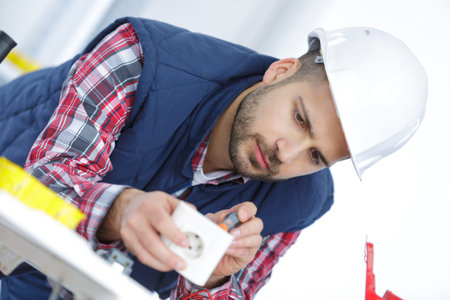 Workman using screwdriver on plug socket