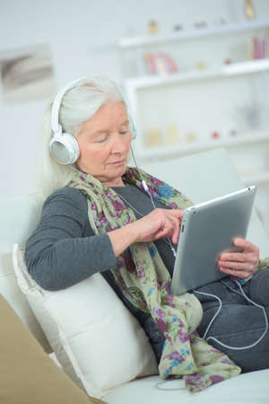 Grandmother using tablet and wearing headphonesの写真素材