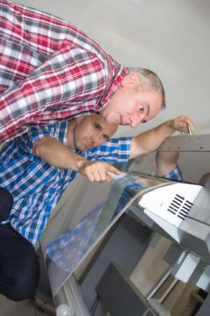 Men examining machineの写真素材