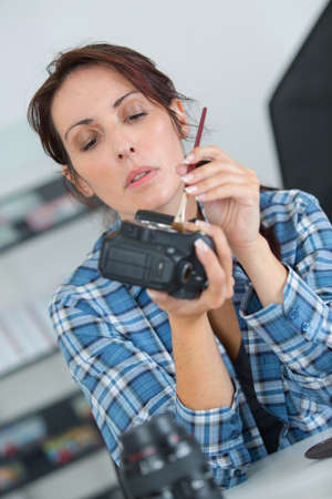 Female technician cleaning camera componentの写真素材
