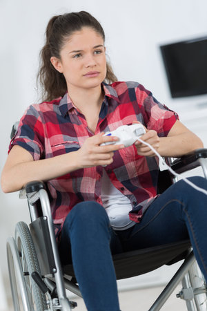 Disabled girl playing computer game, looking forlorn