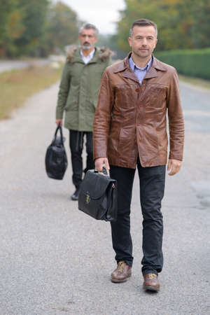 Two men walking, wearing coatsの写真素材