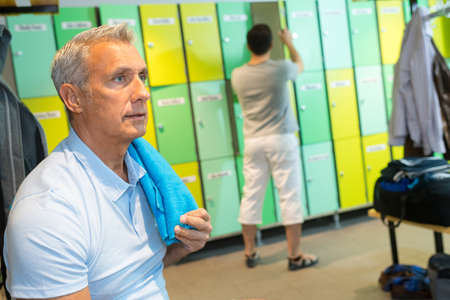 senior man sitting in the locker room in the gymの写真素材
