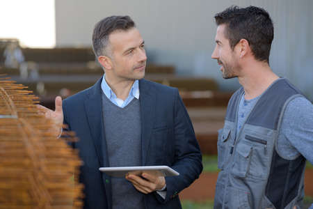 Man holding tablet showing product to workerの写真素材