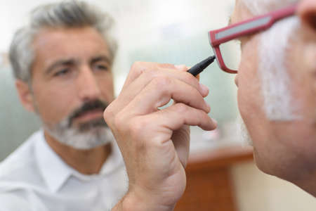 optician using and ophthalmoscope to look into a patients eyesの写真素材