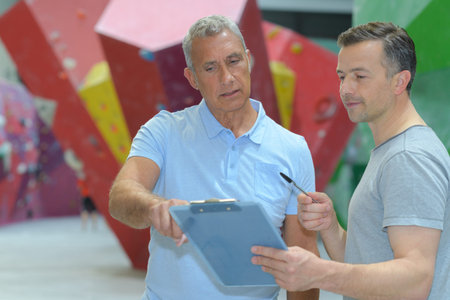 instructor guiding senior man on rock climbing wall