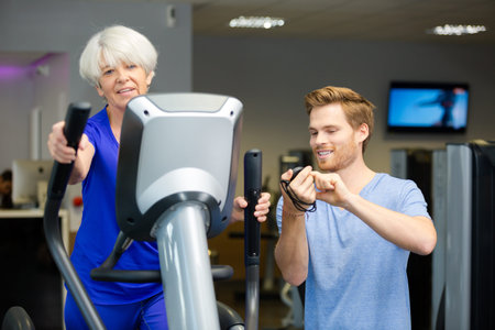 elderly lady working-out with a friendly young male trainer