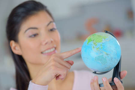 happy female pointing on a globe for holidaysの写真素材