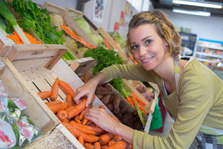 smiling female seller in vegetables marketの写真素材