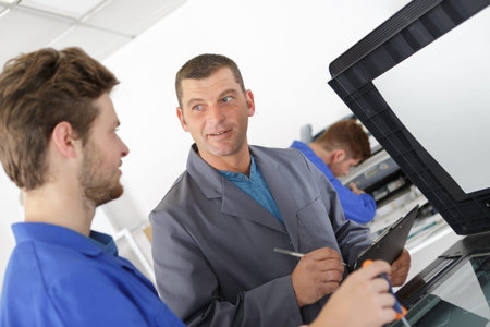 young apprentice repairing photocopier with instructorの写真素材
