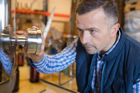 attentive brewer checking pressure at breweryの写真素材