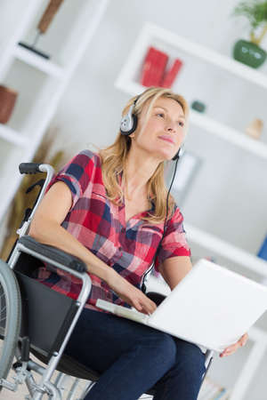 disabled woman in wheelchair with laptop and headphonesの写真素材