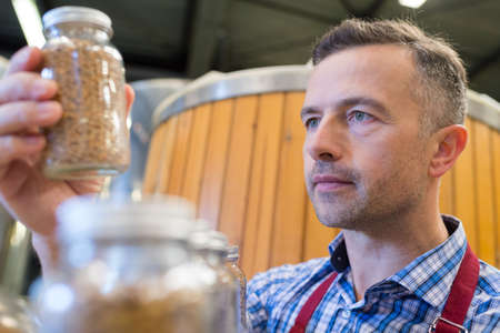 Worker looking at ingredient in glass jarの写真素材