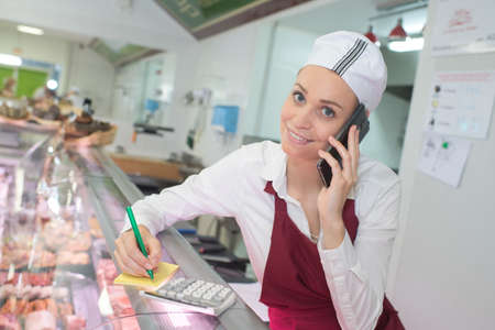 Woman in butchers taking phone orderの写真素材