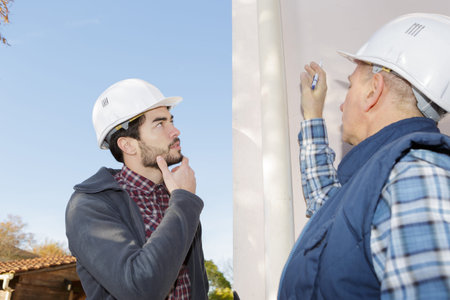 worker and his apprentice inspecting a gutter prior to work