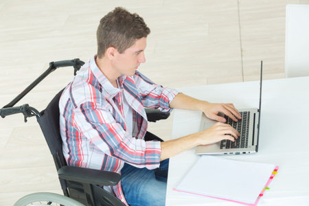 student in wheelchair typing on his laptop