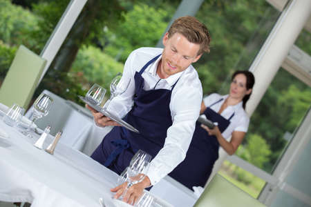 waiter setting wedding table at restaurantの写真素材