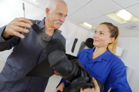 female mechanic in auto repair shop with senior workerの写真素材
