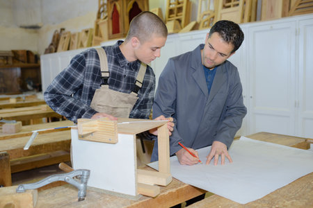 carpenter with apprentice in workshop