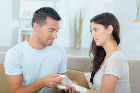 young man bandaging his girlfriend after an injuryの写真素材