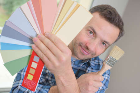 house decorator holding a color swatch and a paint rollerの写真素材