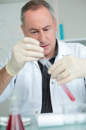 doctor holding red blood in test tube on white background