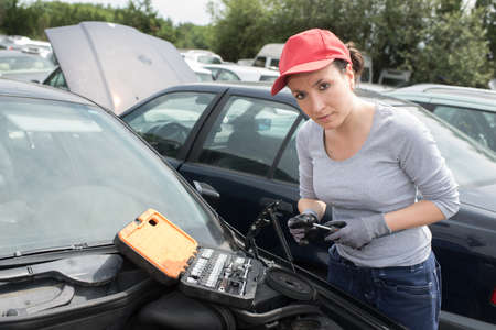 female mechanic changing tire with wheel wrenchの写真素材