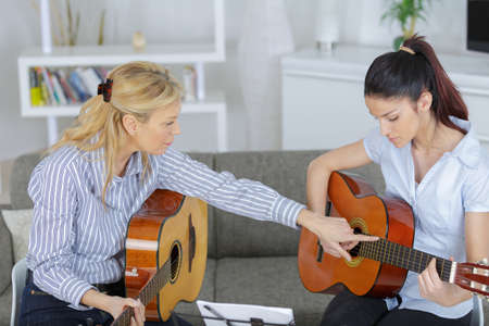 young woman learning to play guitarの写真素材