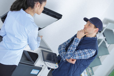 Office worker and contractor in discussion by photocopy machine