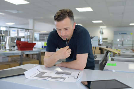 man working on blueprint in officeの写真素材