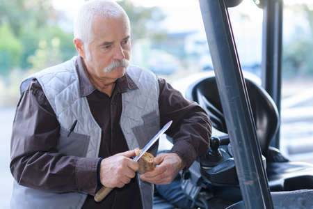 experienced forklift driver outside his forklift in a warehouseの写真素材