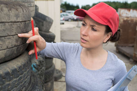 woman checking tread on car tyre with gaugeの写真素材