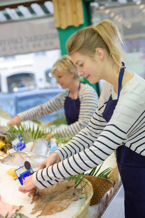 portrait of two sellers in fish section of supermarketの写真素材