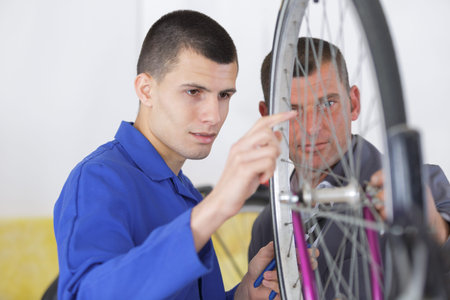 bicycle mechanic and apprentice repairing a bike in workshop