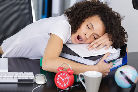 tired businesswoman falling asleep at her workplace