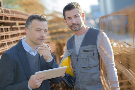 Two workers working outside in a construction site