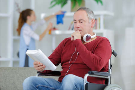 frustrated man in wheelchair reading bookの写真素材