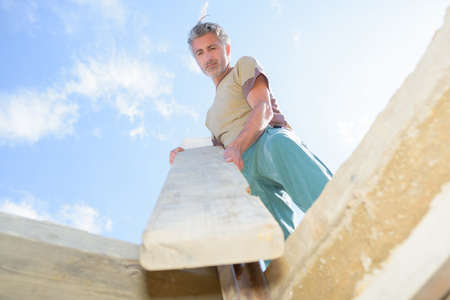 Carpenter or homeowner fitting a section of woodの写真素材