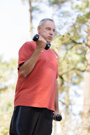 senior man training and lifting dumbbells
